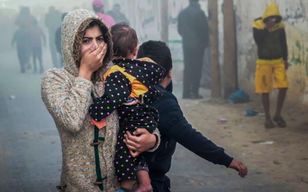 A woman holding a child flees following an Israeli strike in Rafah in the southern Gaza Strip on November 23, 2023, amid o<em></em>ngoing battles between Israel and the Palestinian militant group Hamas. (Photo by Mohammed ABED / AFP)