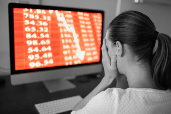 21_06_10 A person holding their face with a computer showing stock losses in the background _GettyImages-1213023814