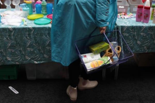 A woman carries a shopping basket co<em></em>ntaining baby items