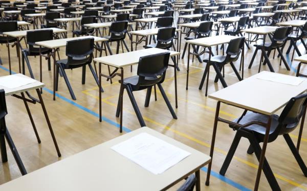 View of large exam room hall and examination desks tables lined up in rows ready for students at a high school to come and sit their exams tests papers.