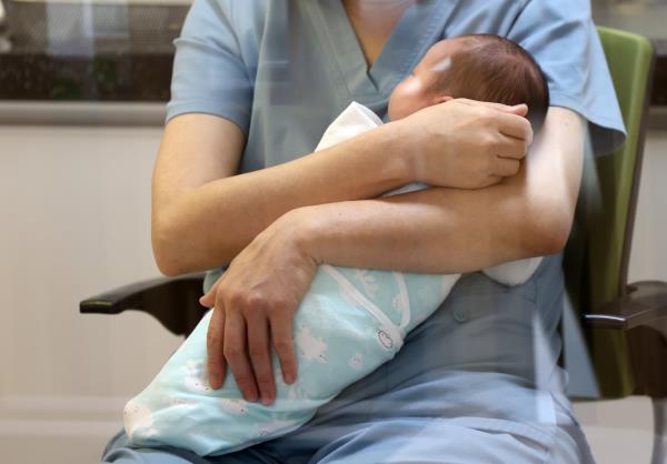 A newborn baby is held by an employee of a postpartum care center in Yanggu-gun, Gangwon Province, Dec. 4. (Yonhap)