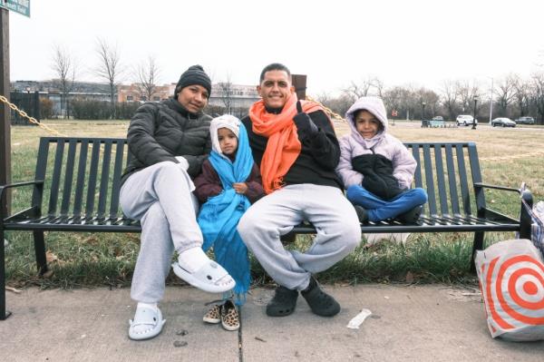 Saray Oliveros sitting on a bench with her daughters and a man after receiving donations.