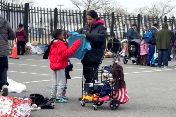 Migrant children and an adult looking at do<em></em>nated clothing they picked up from volunteers.