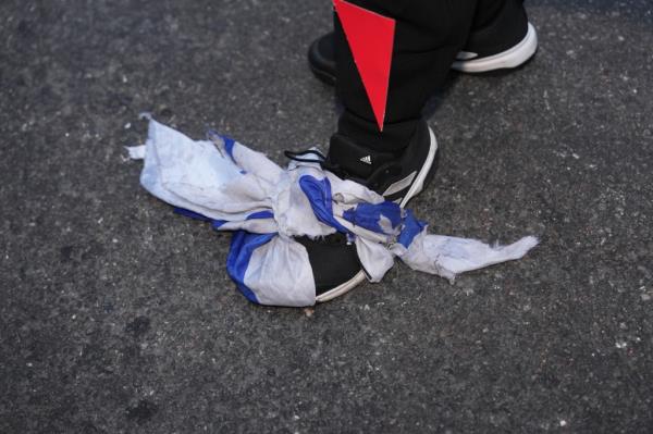 A protestor stepping on what appears to be a Israeli flag.