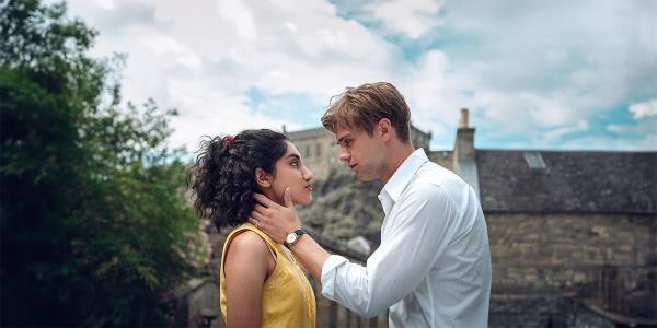 Leo Woodall as Dexter and Ambika Moda as Emma looking at each other with scenery behind them in One Day show