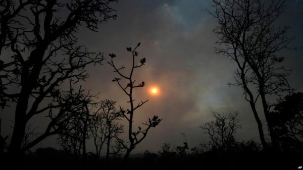 FILE - The sun sets behind the smoke of large-scale fires in the native Cerrado forest at the Natio<em></em>nal Park in Brasilia, Brazil, Sept. 5, 2022.