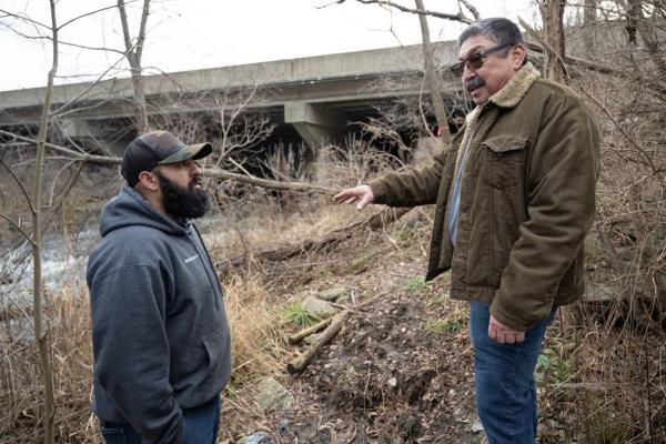 Hobart resident Mario Garcia, on right, and his son-in-law Nivardo De La Torre recount the moment they spotted the wrecked truck that trapped Mishawaka resident Matthew Reun for 6 days, as they revisit the site of the crash on Wednesday, December 27, 2023. (Kyle Telechan for the Post-Tribune)