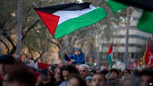 A boy waves a Palestinian flag as demo<em></em>nstrators march during a protest in support of Palestinians and calling for an immediate cease-fire in Gaza, in Barcelona, Spain, Jan. 20, 2024.