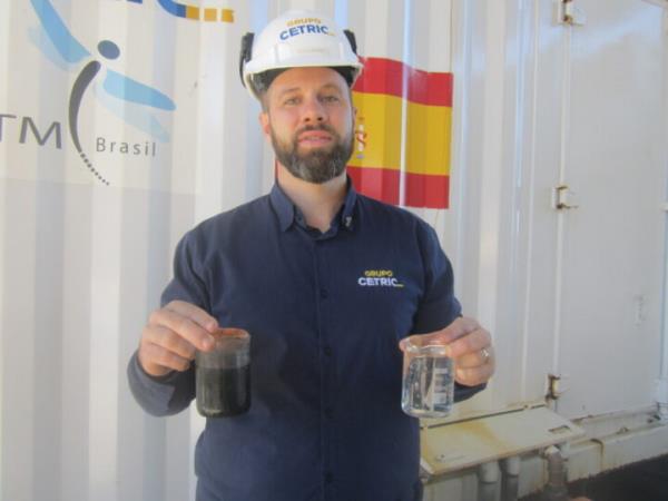 Diego Molinet, a chemical engineer at Cetric, holds in his hands the result of the treatment of effluents from the industrial waste treatment process, with production of biogas and biomethane: a glass with clean water for non-potable reuse and another glass with solid material that can be co<em></em>nverted into fertilizer after composting. CREDIT: Mario Osava / IPS