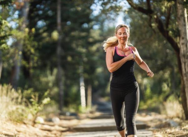 middle-aged woman jogging or running outdoors, co<em></em>ncept of workout to lose body fat in your 40s