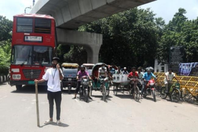 A young man directs traffic on a busy road. 