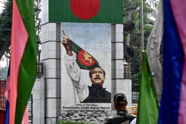 A mural of a man pointing with the Bangladesh flag behind him and the words 'Father of the nation Bangabandhu Sheikh Mujibur Rahman' below the picture.