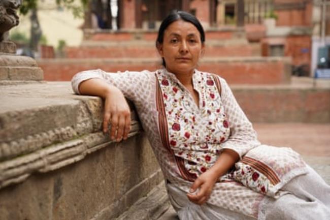 Devi Khadka sits on a stone bench in a public square in Kathmandu