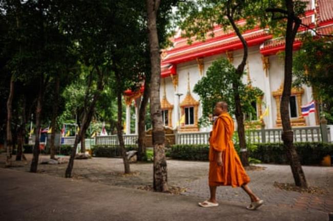 A monk in a saffron robe walks through a Buddhist temple