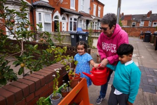 Jan Burley helps children water new fruit trees and plants