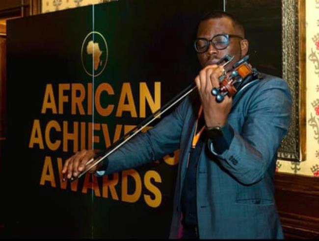 An African man wearing glasses plays a viola.