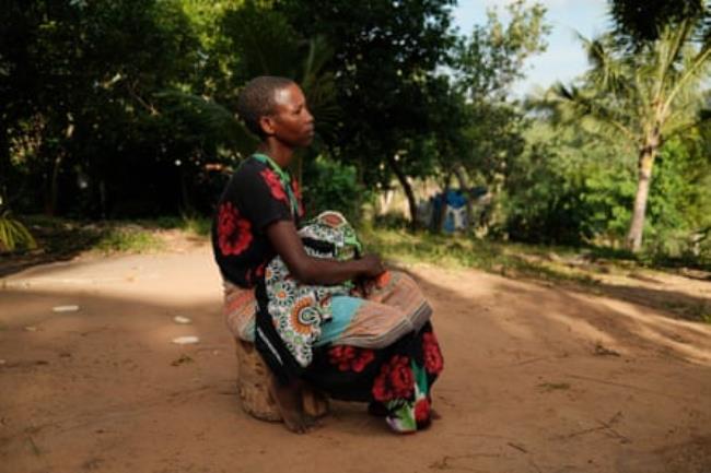 A woman sits holding a baby.