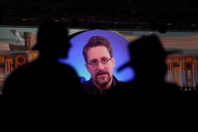 Edward Snowden on screen with people silhouetted in front of him