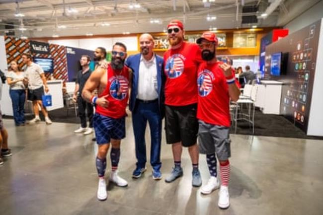 man poses for group photo with three men in red t-shirts