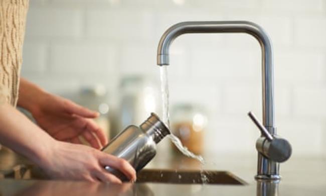 a woman cleans a reusable water bottle