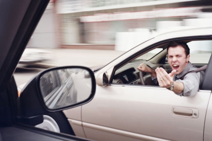 Man driving gesturing angrily at another car