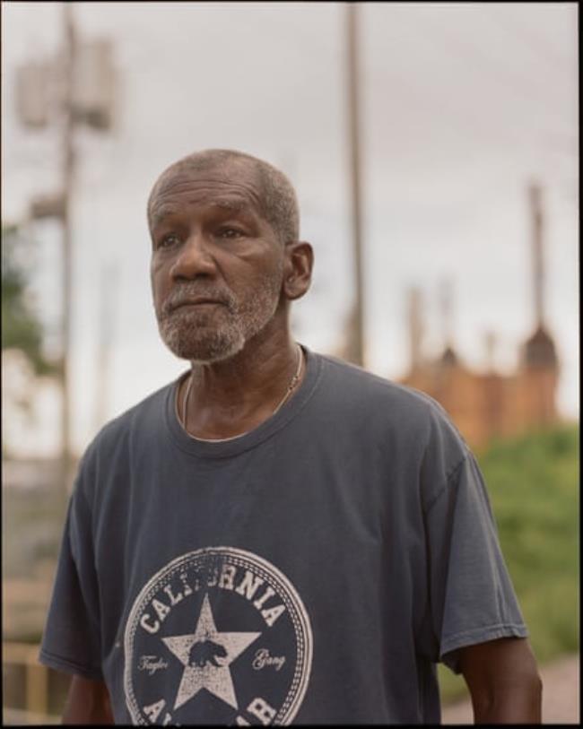 A middle-aged man with a refinery in the background.