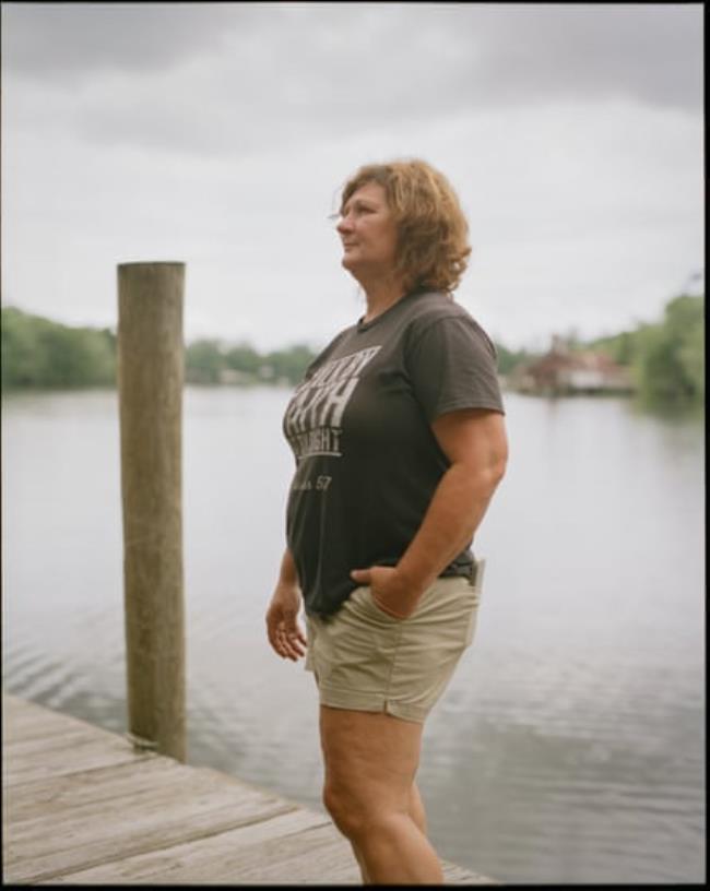 A middle-aged woman on a dock on a body of water.