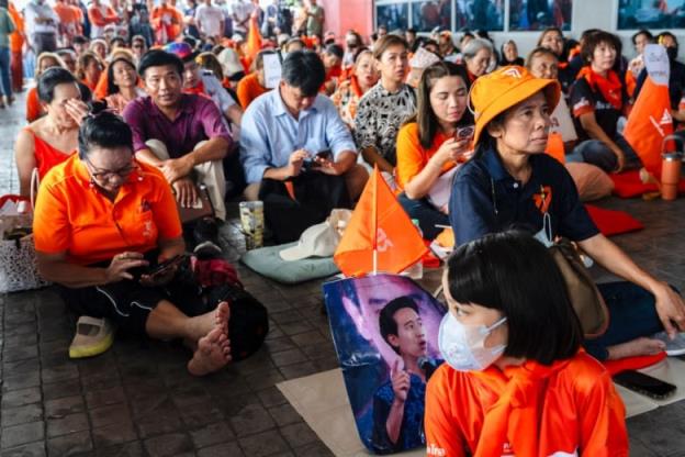 Supporters of Thailand's Move Forward Party sit on the ground outside party headquarters in Bangkok. 