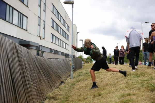 A protester throws a stone at a hotel in Rotherham, Britain, August 4, 2024. REUTERS/Hollie Adams