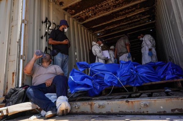 Men prepare to remove bodies from a co<em></em>ntainer after they were taken and later released by Israel, ahead of a mass funeral at a cemetery in Khan Yunis in the southern Gaza Strip on August 5, 2024, amid the o<em></em>ngoing co<em></em>nflict between Israel and the Palestinian Hamas militant group. (Photo by Bashar TALEB / AFP)