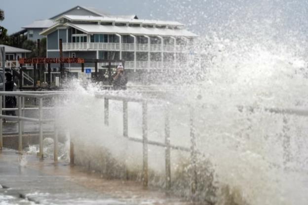 Ocean water splashes in the air along a breakwall.