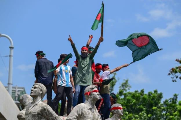 Protesters wave flags as they stand on a monument.