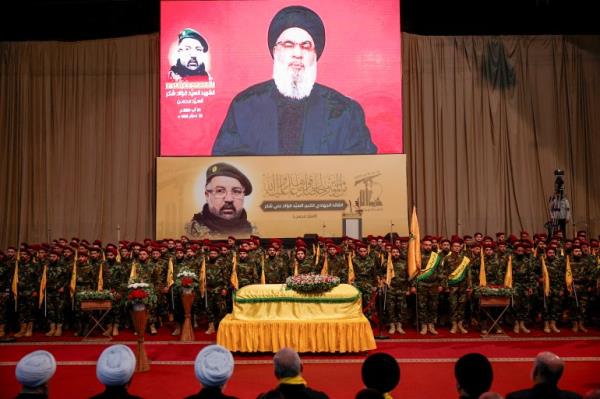 Lebanon's Hezbollah leader Sayyed Hassan Nasrallah addresses his supporters via a video display on screen during the funeral of Hezbollah senior commander Fuad Shukr,