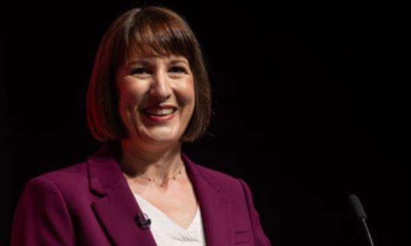 Rachel Reeves smiling, photographed against a dark background