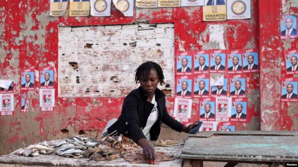 A woman prepares her stall, with election posters in the background, ahead of the presidential elections, in the suburb of Katembe, Maputo, Mozambique, Oct. 7, 2024. Voting opens across the country on Oct. 9, 2024. 