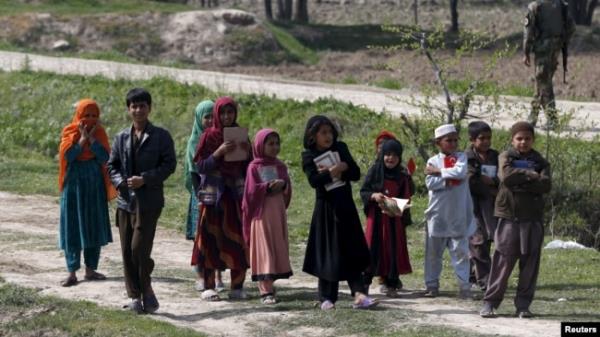 FILE - Afghan children hold the Quran as they go to a madrassa, or religious school, in Dand Ghori district in Baghlan province, Afghanistan, March 15, 2016.