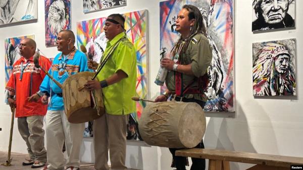 FILE - Native American climate activist and artist Jacob Johns, right, drums with members of the Santa Clara Pueblo tribe of New Mexico in Santa Fe, July 11, 2024. Johns was shot at a protest in the state in 2023.