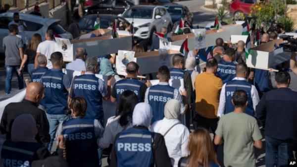 FILE - Palestinian journalists carry mock coffins of colleagues killed during the current Israel-Hamas war, during a symbolic funeral procession in the West Bank city of Ramallah, Nov. 7, 2023.