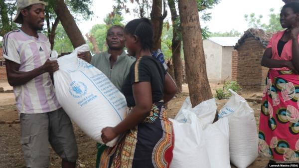 Beneficiaries of emergency food assistance in Malawi's Chikwawa district take home bags of maize provided by the United Nations' World Food Program on Oct. 2, 2024. (Lameck Masina/VOA)