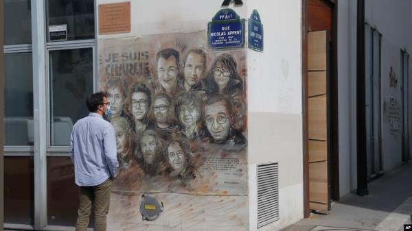 A man looks at a painting by French street artist Christian Guemy, aka "C215," in Paris on Sept. 2, 2020, in tribute to the members of the satirical newspaper Charlie Hebdo attack by jihadist gunmen in January 2015.