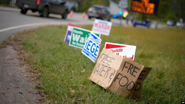 FILE - A makeshift cardboard sign leans up against campaign posters near a relief center on Oct. 3, 2024, in Vilas, N.C., in the aftermath of Hurricane Helene. 