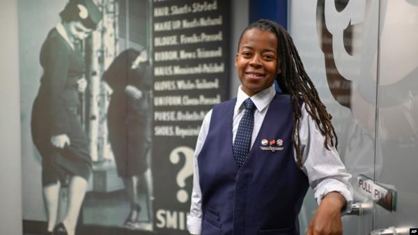 Keturah Johnson, internatio<em></em>nal vice president for flight attendant unio<em></em>n AFA-CWA, poses by a decades-old, outdated poster a<em></em>bout rules and uniforms for flight attendants, at her headquarters office in Washington, Sept. 18, 2024. 