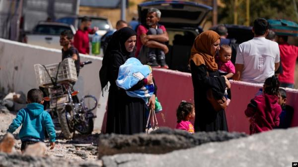 People carry their luggage as they cross into Syria on foot, through a crater caused by Israeli airstrikes aiming to block Beirut-Damascus highway at the Masnaa crossing, in the eastern Bekaa Valley, Lebanon, Oct. 5, 2024.