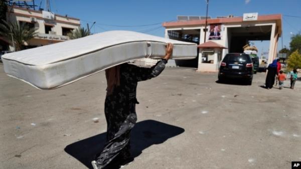 A Syrian woman fleeing the war in Lebanon carries a mattress as she arrives at the Syrian-Lebanese border crossing in Jousieh, Syria, Oct. 2, 2024.