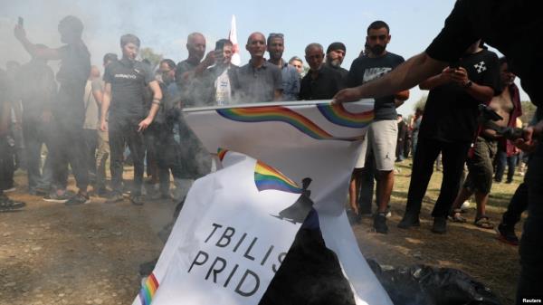 FILE - Anti-LGBTQ+ protesters who managed to break through a police cordon use LGBTQ+ signage to make a bo<em></em>nfire in an area designated for the Tbilisi Pride Fest, in Tbilisi, Georgia, July 8, 2023.