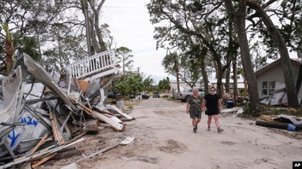 Charlene Huggins, and her daughter-in-law, Katelyn Huggins, right, walk past the destruction on their street in the aftermath of Hurricane Helene, in Horseshoe Beach, Florida, Sept. 28, 2024.