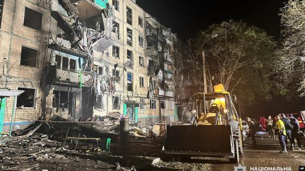 People gather around the damage and debris after a Russian strike on a residential building in Kharkiv, Ukraine, Oct. 2, 2024. 