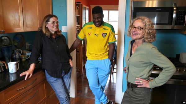 Cabrel Ngounou, center, a refugee from Cameroon, talks with his sponsors, Lori Ostlund, left, and Anne Raeff, in their home in San Francisco on Sept. 17, 2024.