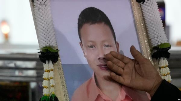 A relative touches a portrait of a victim of a school bus fire at Wat Khao Phraya Sangkharam School Lan Sak, Uthai Thani province, Thailand, Oct. 3, 2024. 