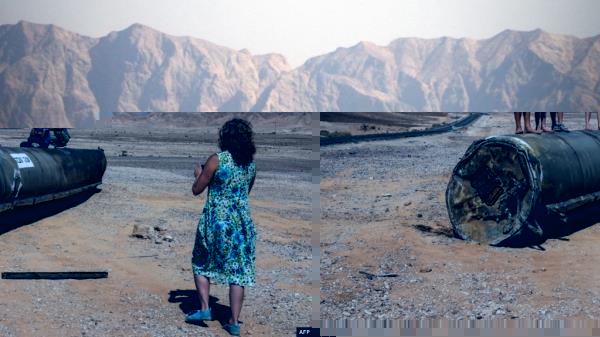 People stand on top of the remains of an Iranian missile in the Negev desert near Arad, on October 2, 2024, in the aftermath of an Iranian missile attack on Israel.